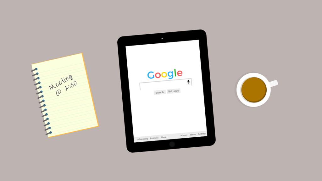 A workspace with an iPad with Google app open and a notepad and coffee mug on the side