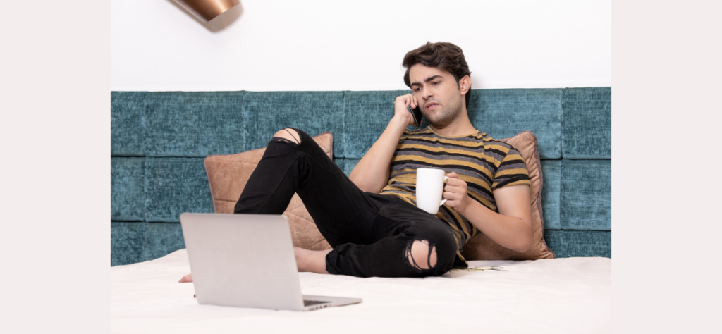 A man making a phone call while seated on the bed